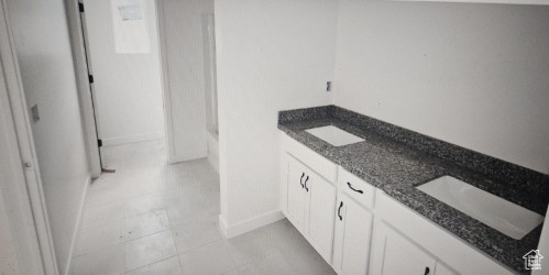 Full bath with baseboards and double vanity