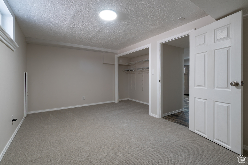 Unfurnished bedroom featuring carpet floors, a textured ceiling, and a closet
