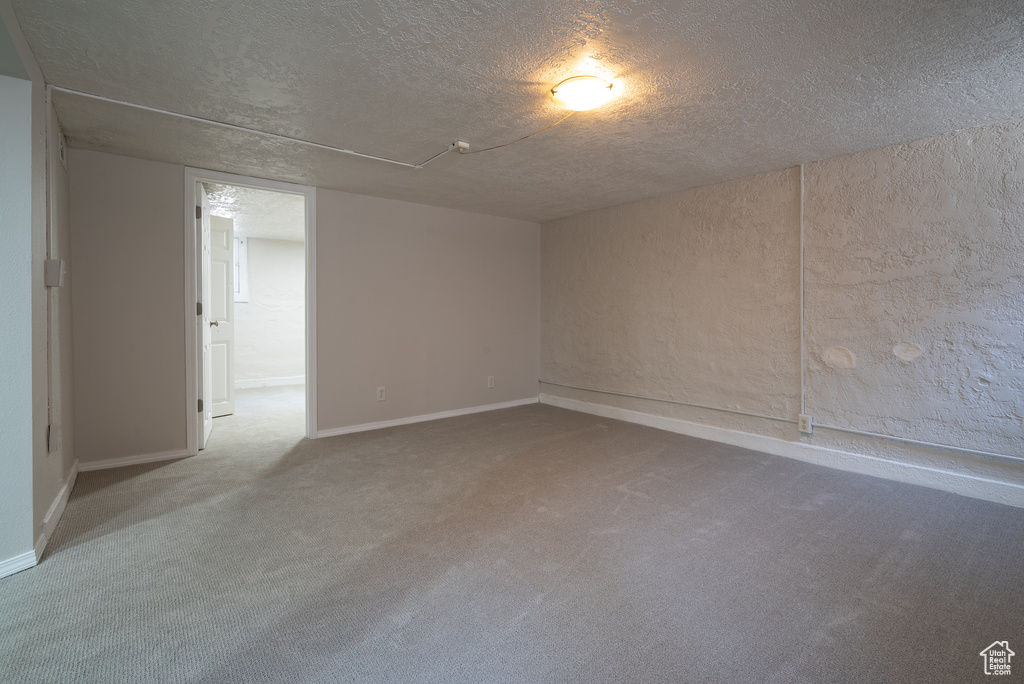 Carpeted spare room with a textured ceiling and baseboards