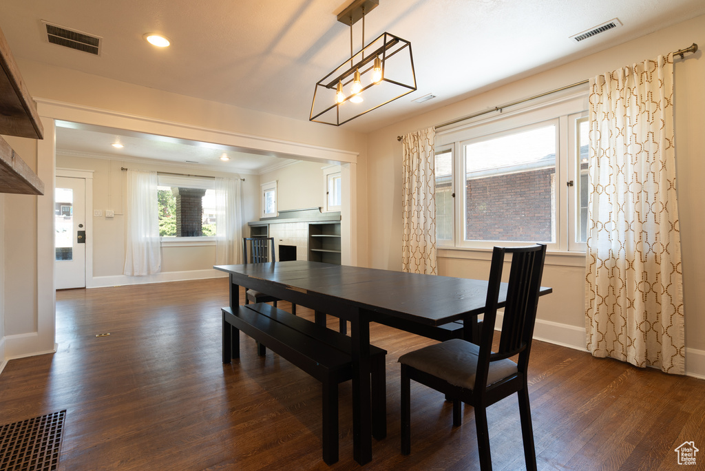 Dining space with dark wood-type flooring, recessed lighting, ornamental molding, and a chandelier