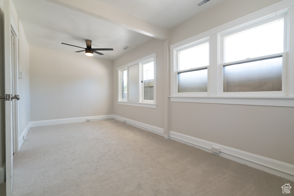 Empty room with ceiling fan and light colored carpet