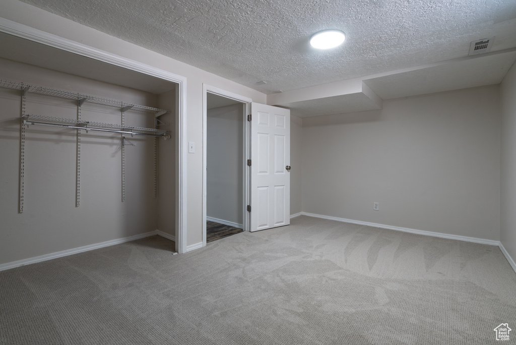 Unfurnished bedroom with carpet, a textured ceiling, and a closet