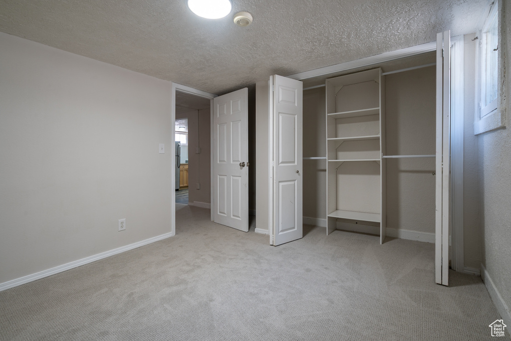 Unfurnished bedroom with carpet floors, a textured ceiling, and a closet