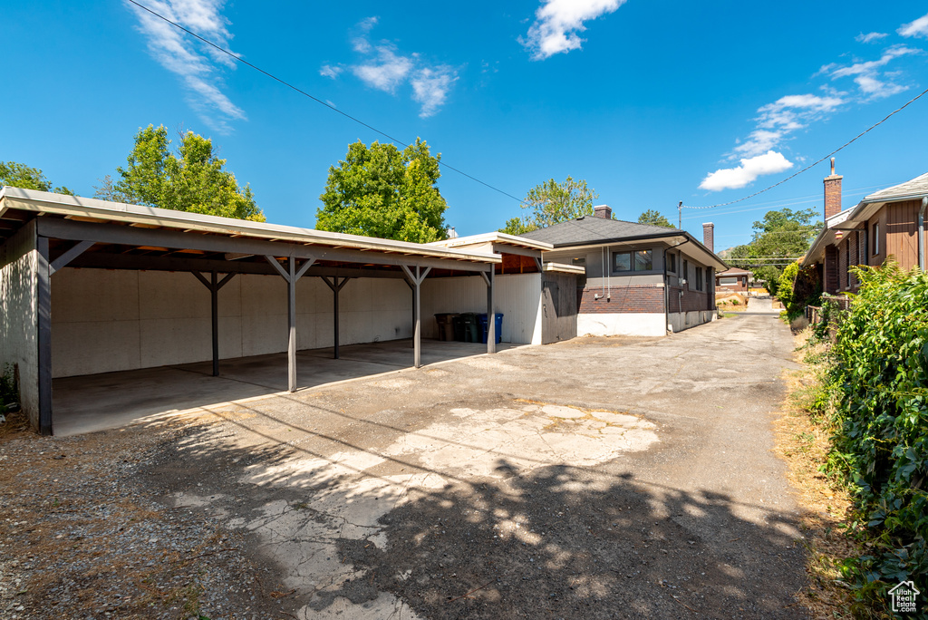 Back of house with asphalt driveway and a detached carport