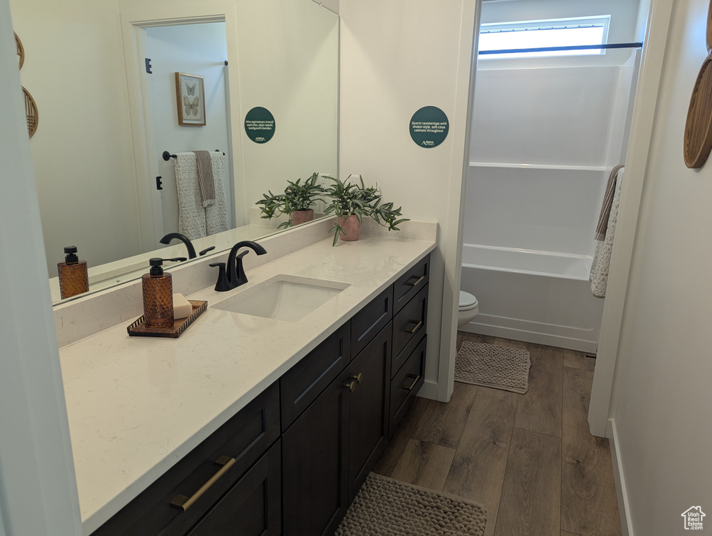 Full bathroom featuring vanity, wood finished floors, and washtub / shower combination