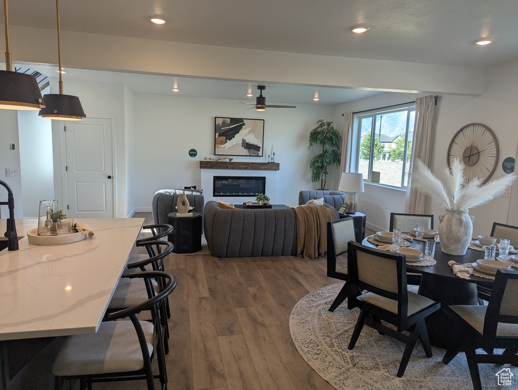 Dining space featuring a glass covered fireplace, ceiling fan, wood finished floors, and recessed lighting