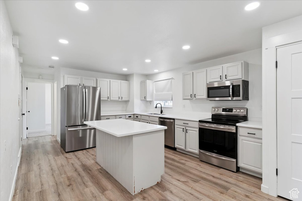 Kitchen featuring appliances with stainless steel finishes, recessed lighting, a center island, light countertops, and light wood-style floors