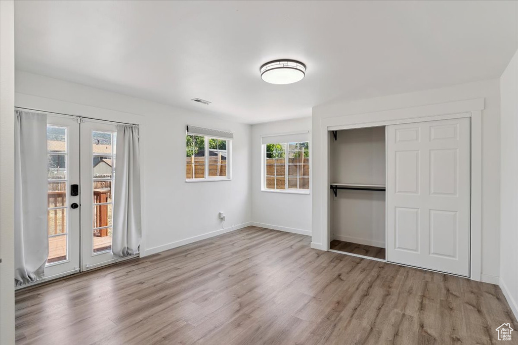 Unfurnished bedroom with access to outside, wood finished floors, french doors, and a closet