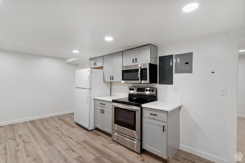 Kitchen featuring stainless steel appliances, electric panel, gray cabinetry, light wood finished floors, and light countertops
