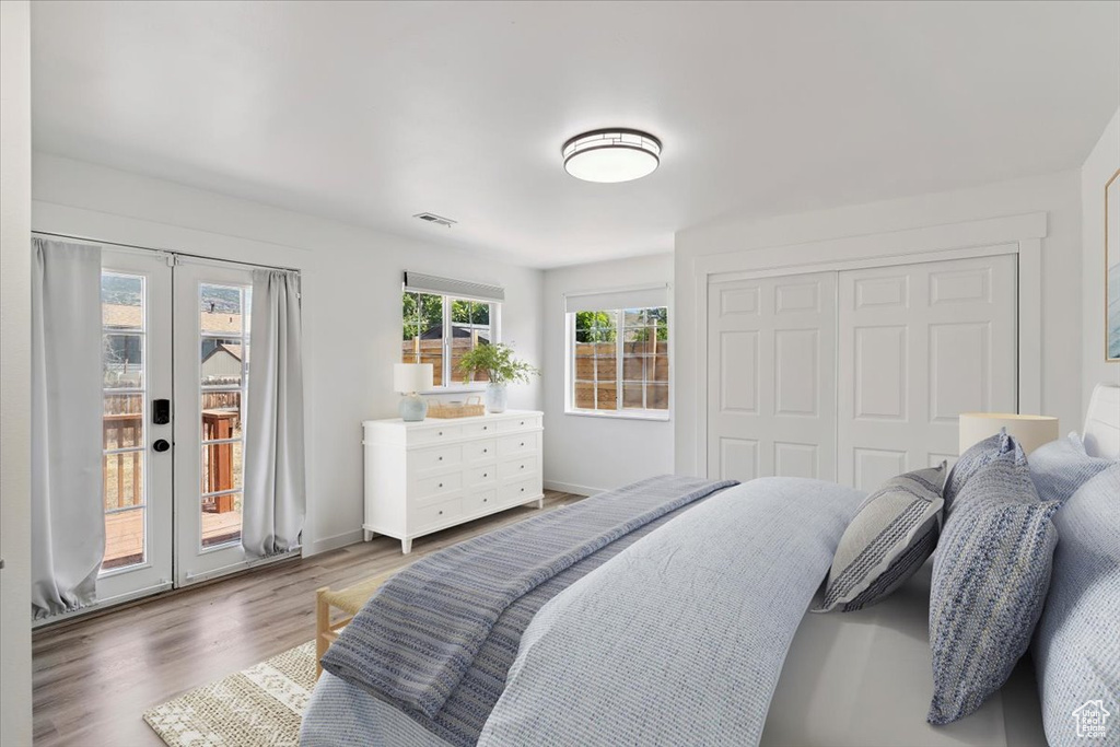 Bedroom with access to exterior, french doors, wood finished floors, and a closet