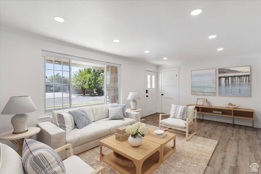 Living room featuring crown molding, recessed lighting, and light wood-type flooring