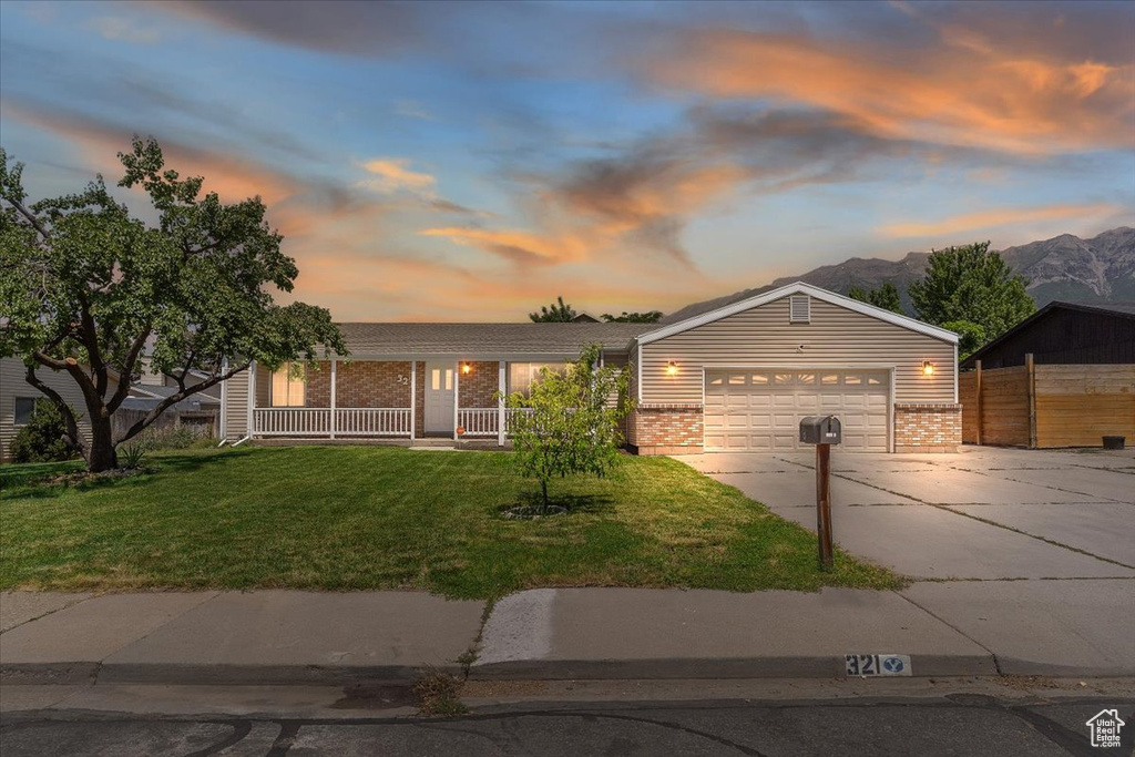 Ranch-style house featuring brick siding, driveway, a garage, a mountain view, and a porch