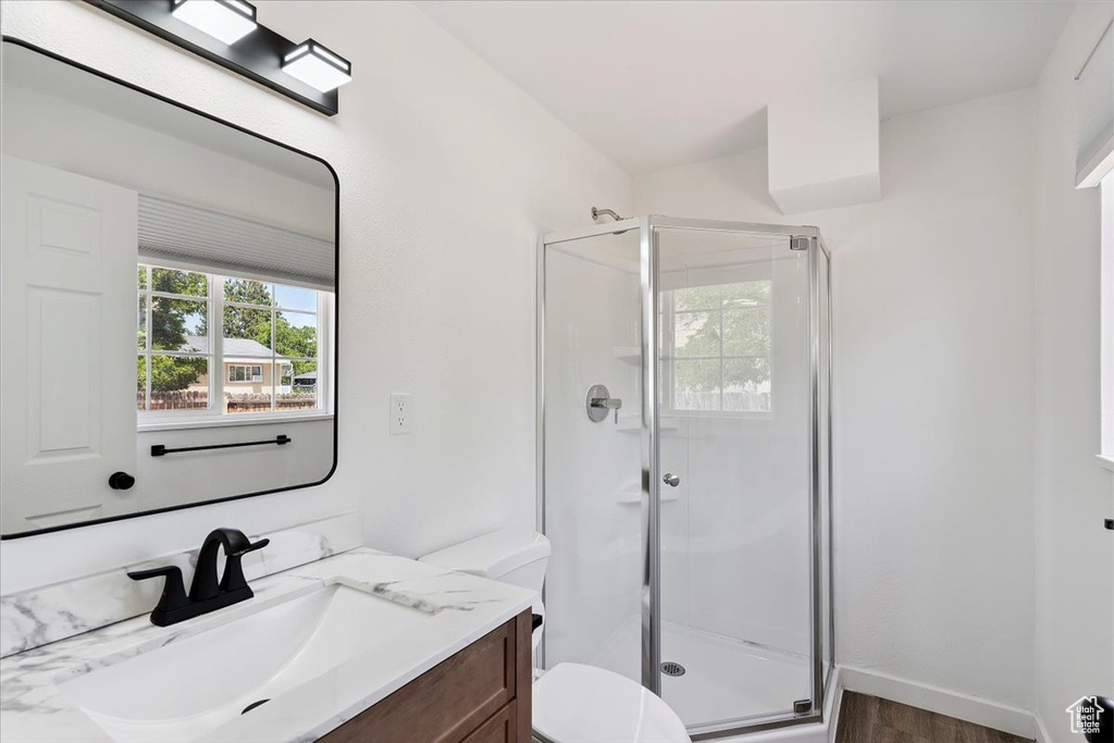 Full bath with a shower stall, vanity, and wood finished floors