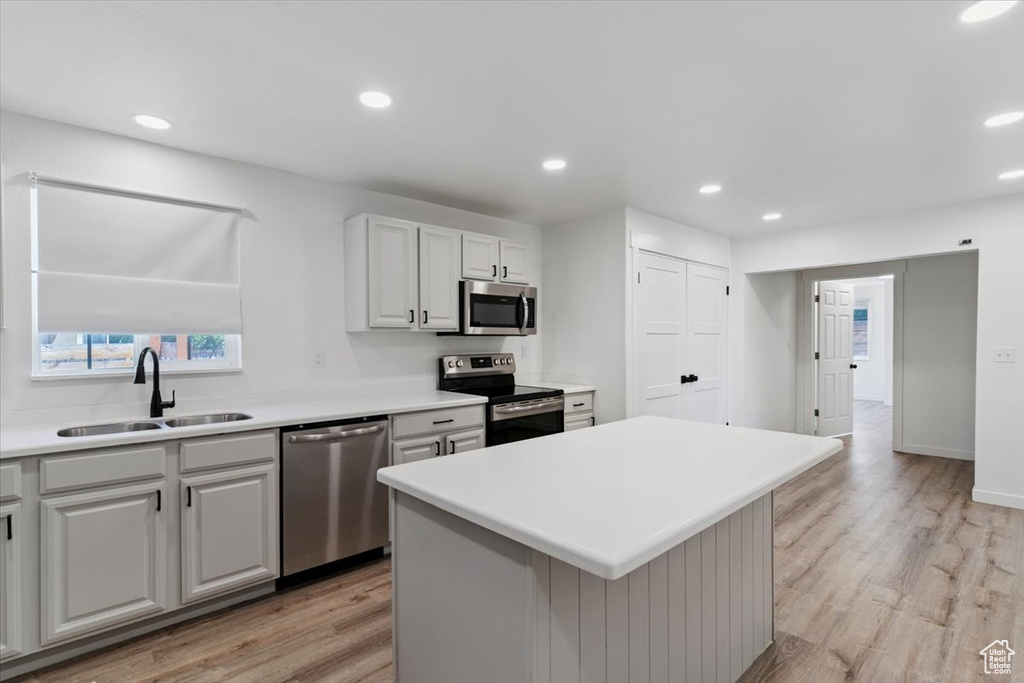 Kitchen featuring appliances with stainless steel finishes, light wood-style floors, recessed lighting, light countertops, and a kitchen island