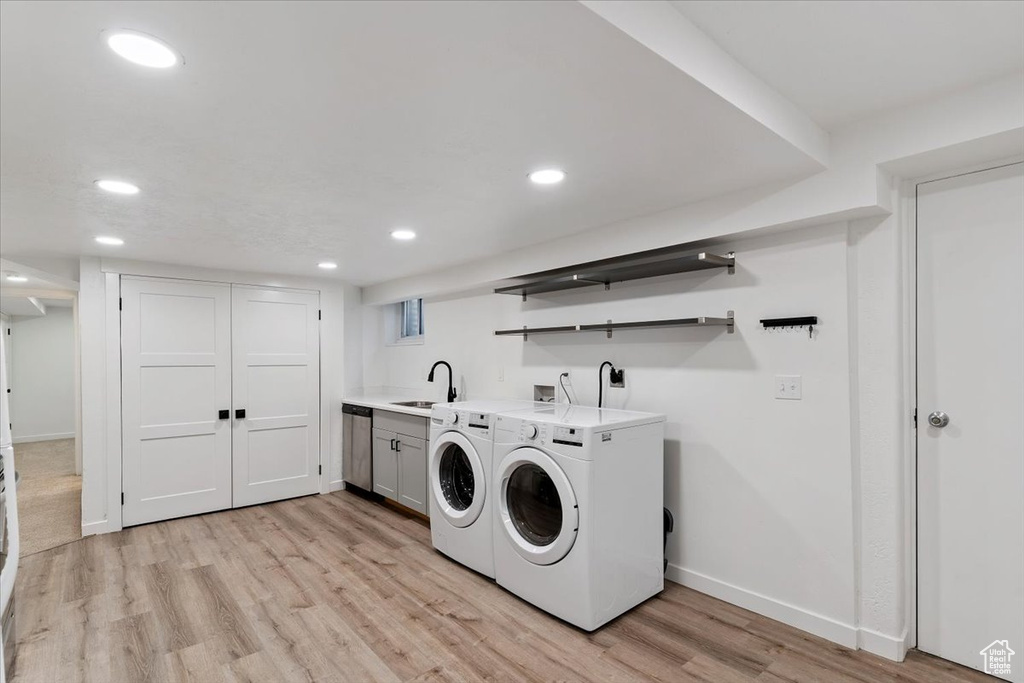 Washroom with cabinet space, light wood-type flooring, washing machine and dryer, recessed lighting, and wet bar