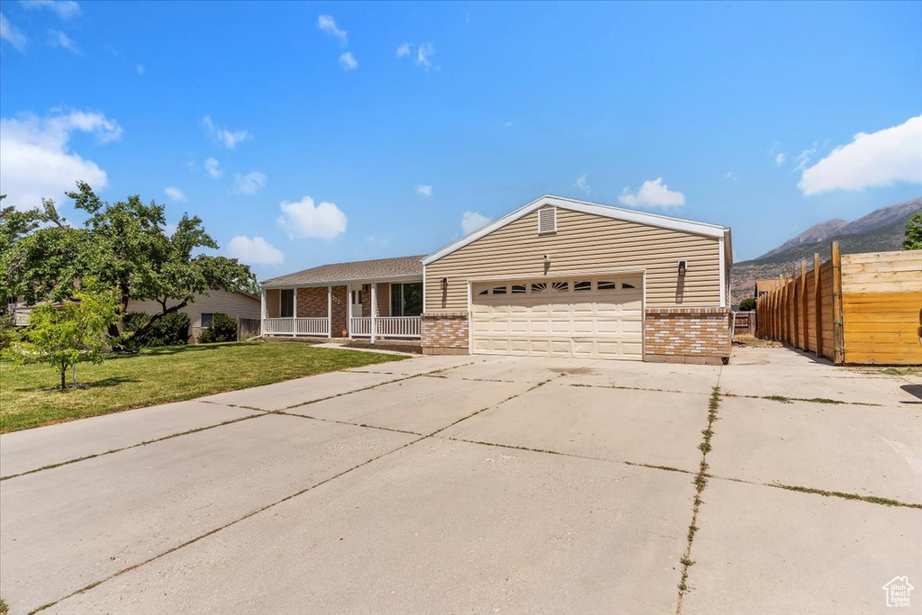 Ranch-style home with brick siding, covered porch, an attached garage, a mountain view, and driveway
