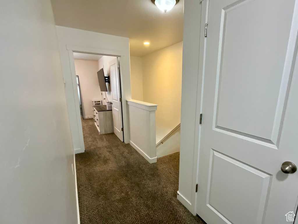 Corridor featuring an upstairs landing and dark carpet