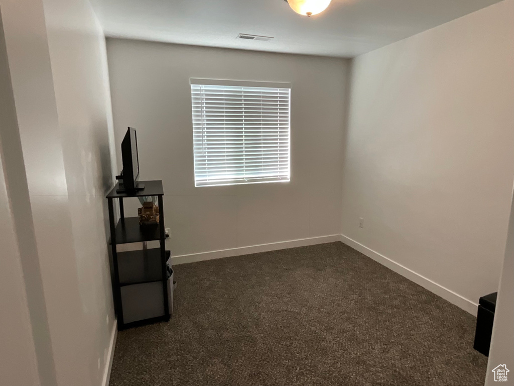 Spare room with dark carpet and baseboards