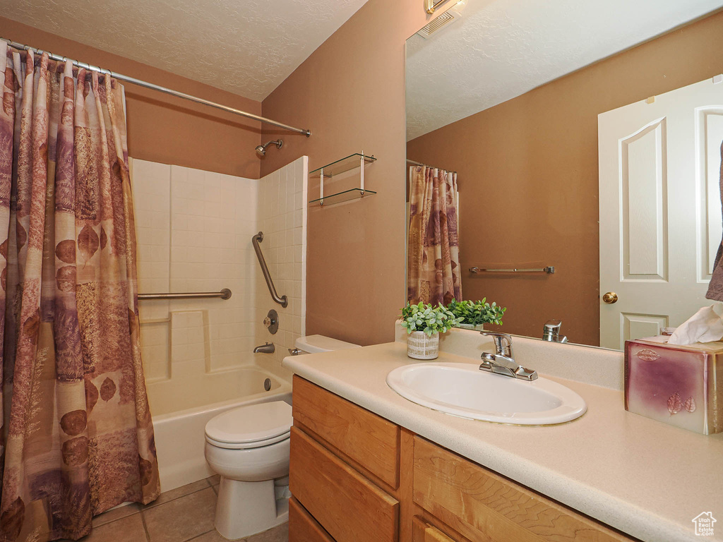 Full bathroom with shower / bathtub combination with curtain, vanity, tile patterned flooring, and a textured ceiling