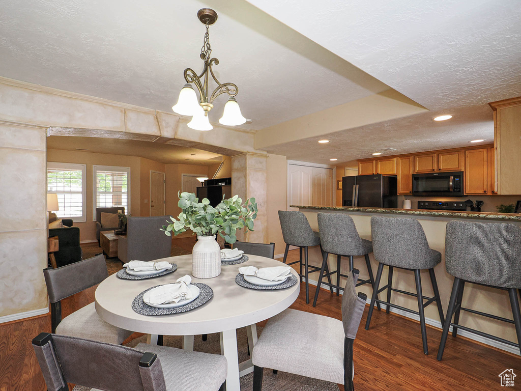 Dining space featuring wood finished floors, a chandelier, a textured ceiling, and recessed lighting