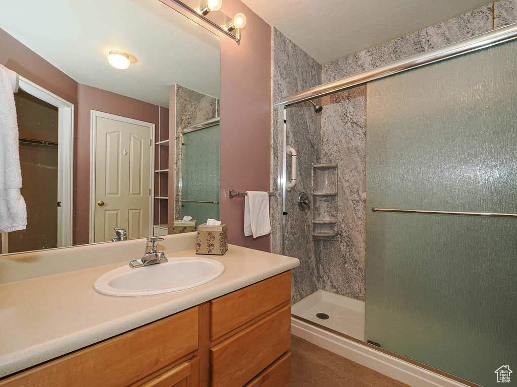 Bathroom featuring a stall shower, vanity, and a closet