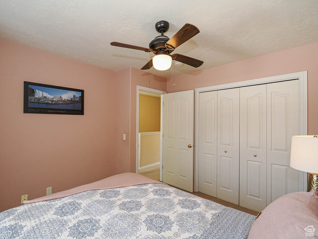 Bedroom featuring a closet, a ceiling fan, carpet, and a textured ceiling