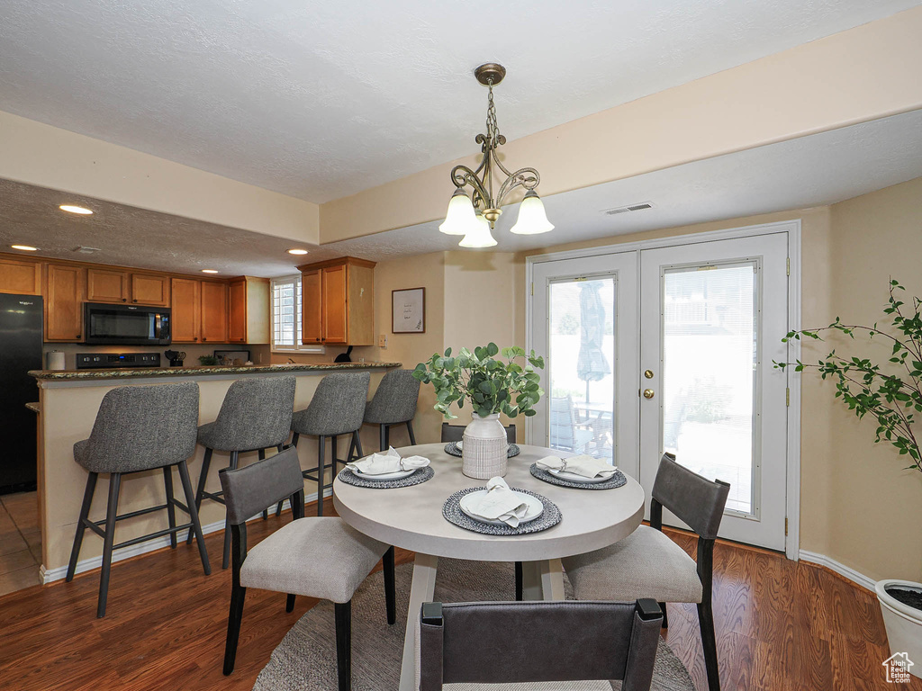 Dining space with a chandelier, wood finished floors, recessed lighting, and french doors