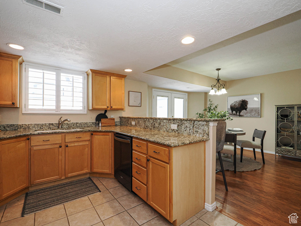 Kitchen with dishwasher, a peninsula, a breakfast bar area, recessed lighting, and dark stone countertops
