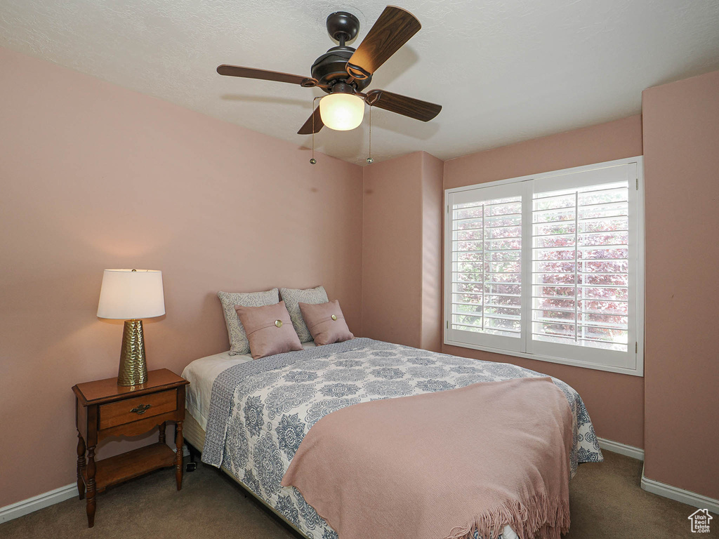 Carpeted bedroom featuring baseboards and a ceiling fan