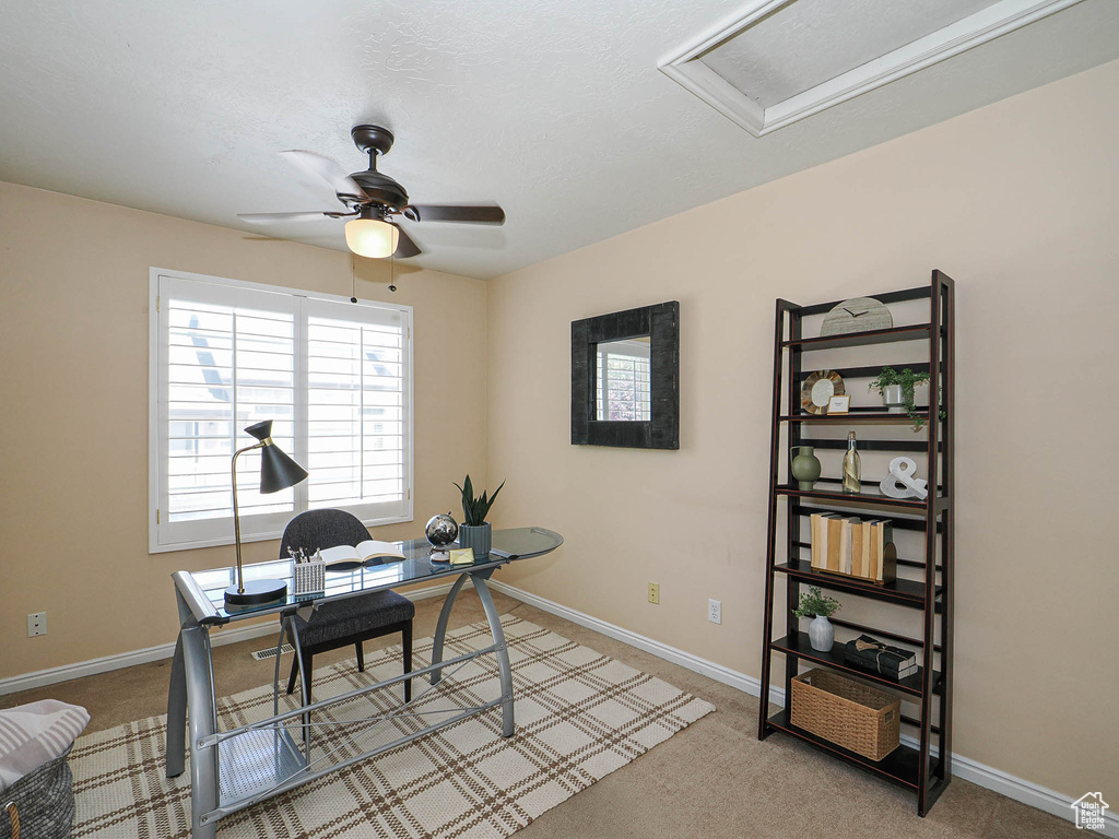 Office area with attic access, a ceiling fan, and carpet flooring