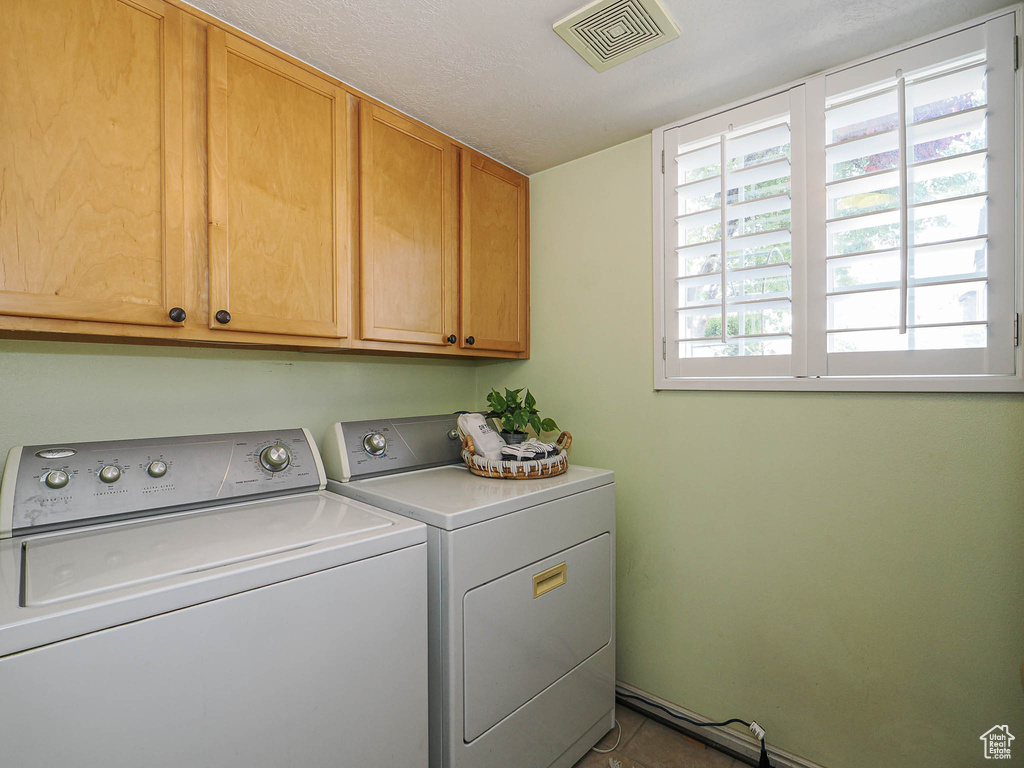 Laundry room featuring cabinet space, separate washer and dryer, and tile patterned floors