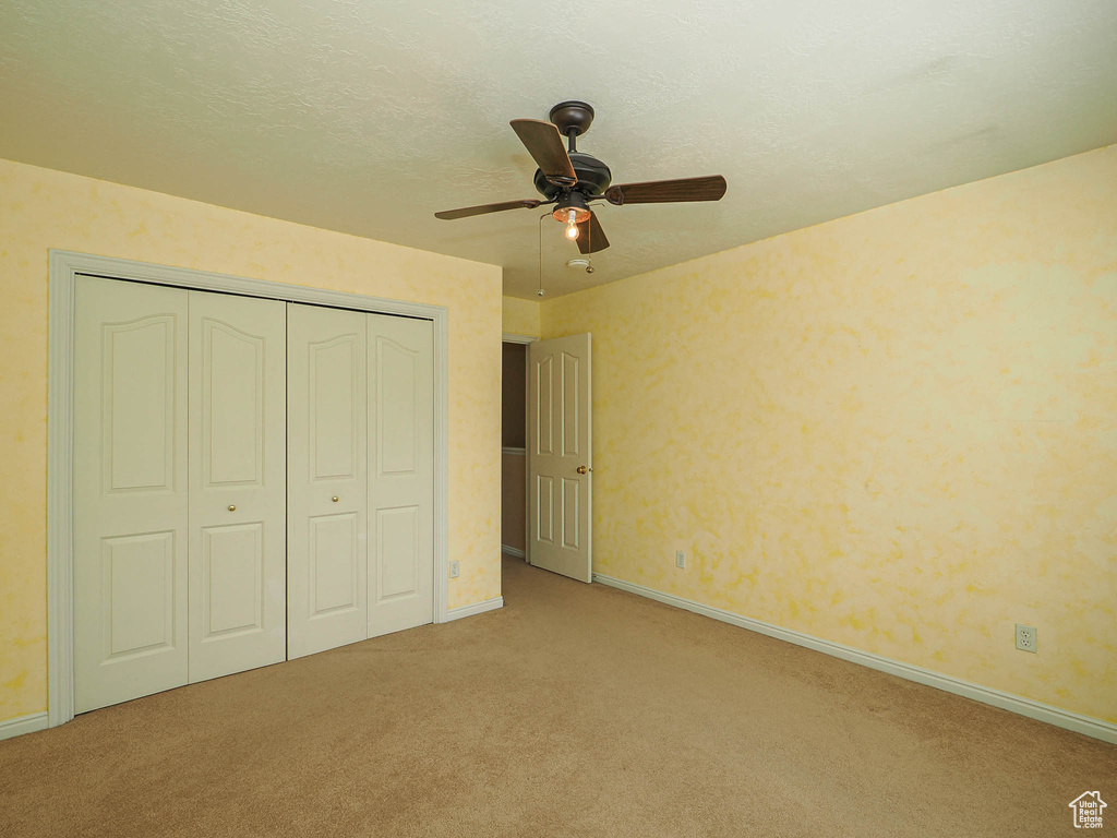 Unfurnished bedroom featuring carpet, a closet, and ceiling fan