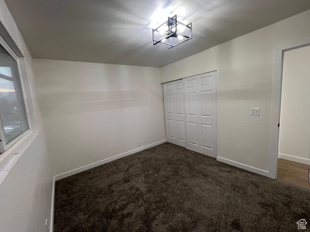 Unfurnished bedroom with dark carpet and a closet