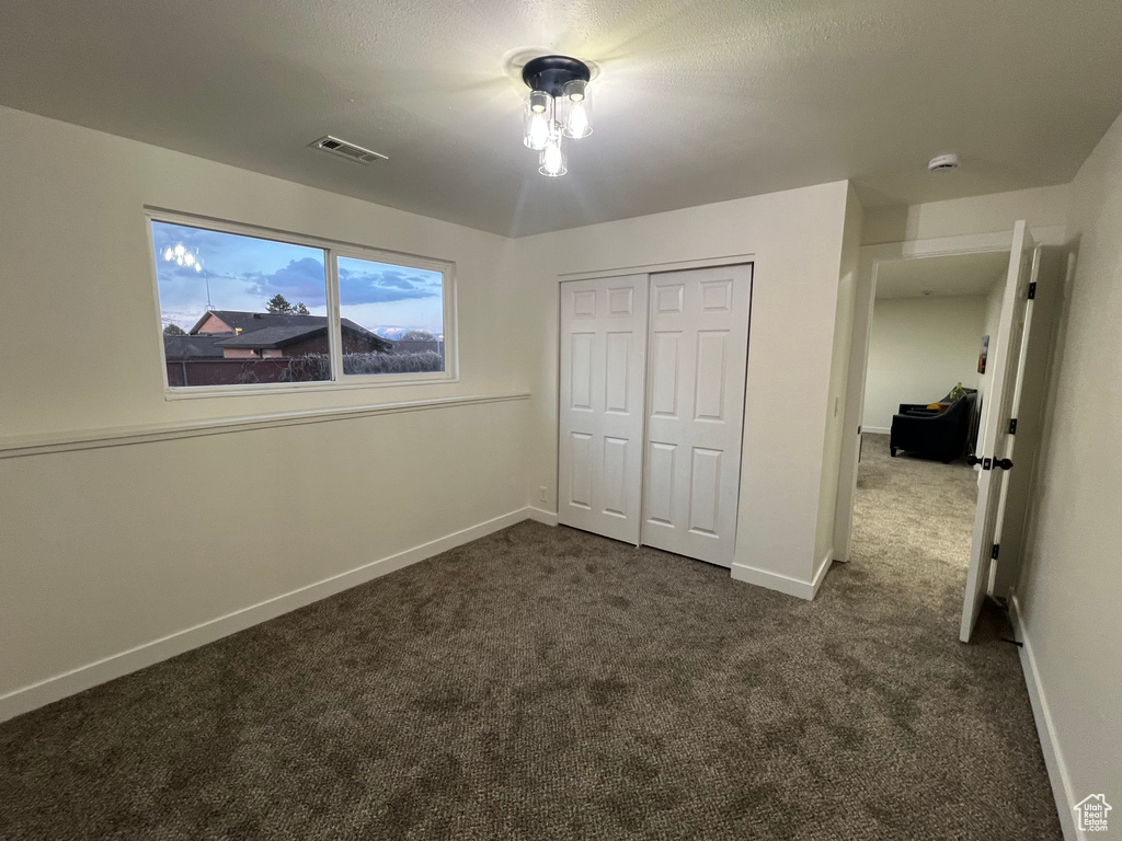 Unfurnished bedroom with dark carpet and a closet