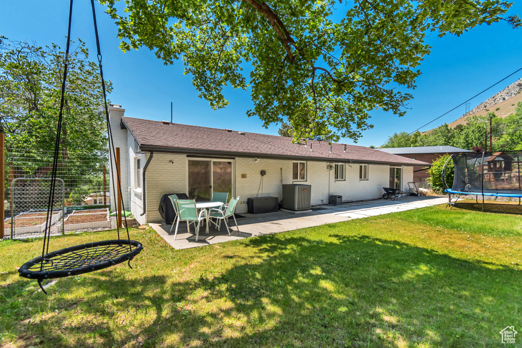 Back of property featuring a trampoline, a patio, a chimney, and a yard