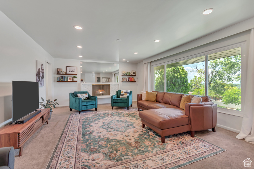Living area featuring light carpet, recessed lighting, and a lit fireplace