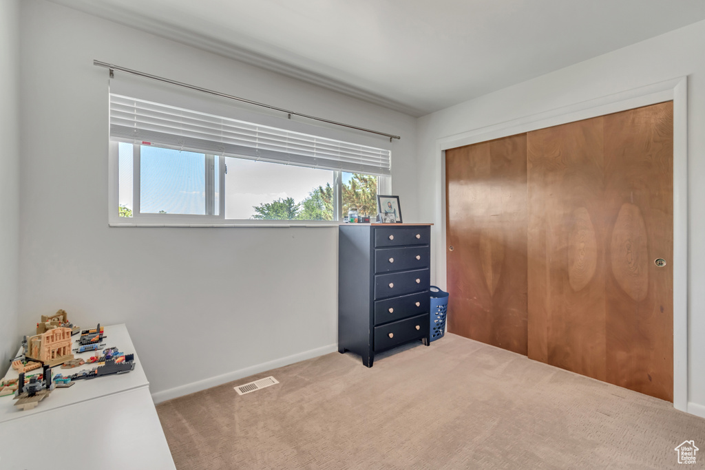 Unfurnished bedroom featuring light carpet and a closet