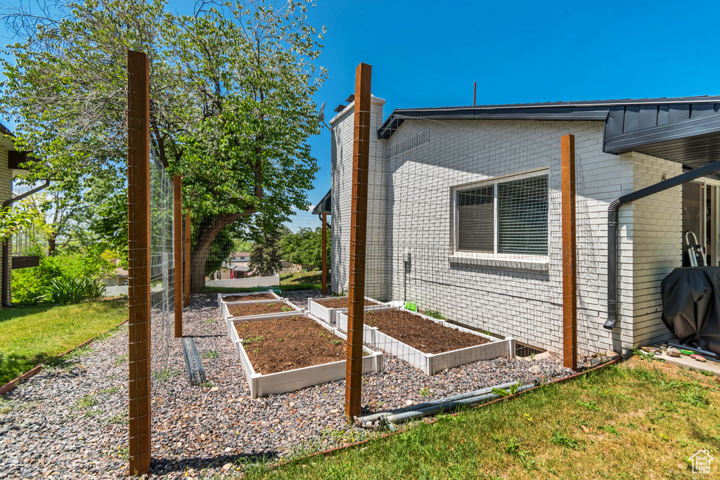 View of side of home featuring a chimney, a vegetable garden, and brick siding