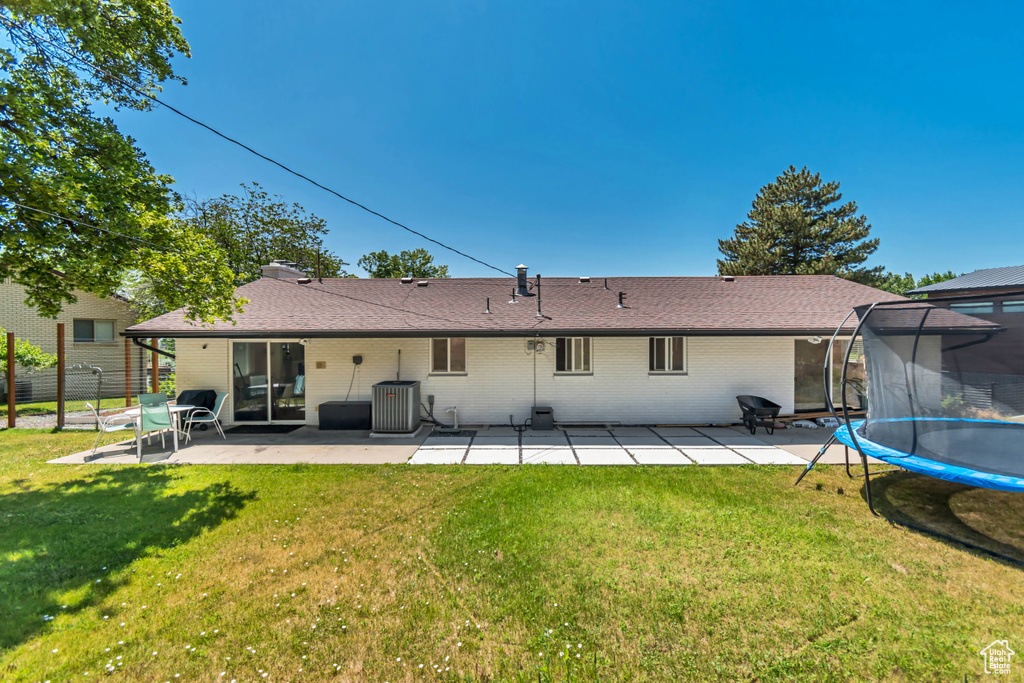 Back of property featuring a patio, a trampoline, and brick siding