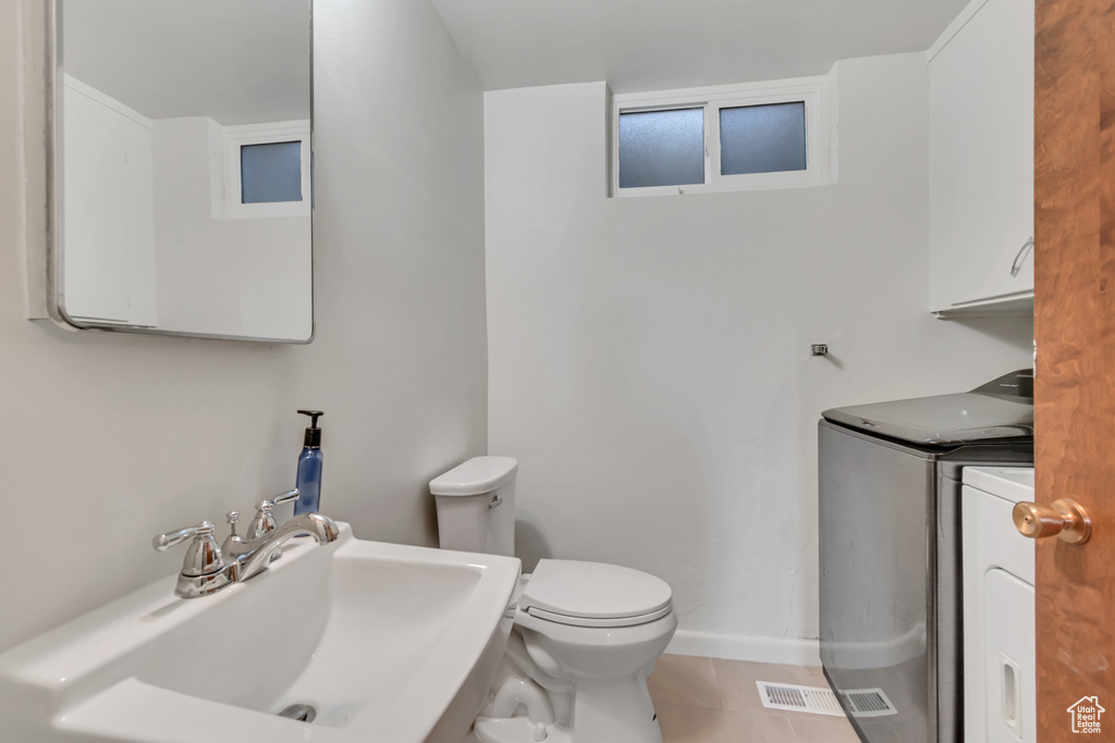 Bathroom with independent washer and dryer, tile patterned floors, and vanity