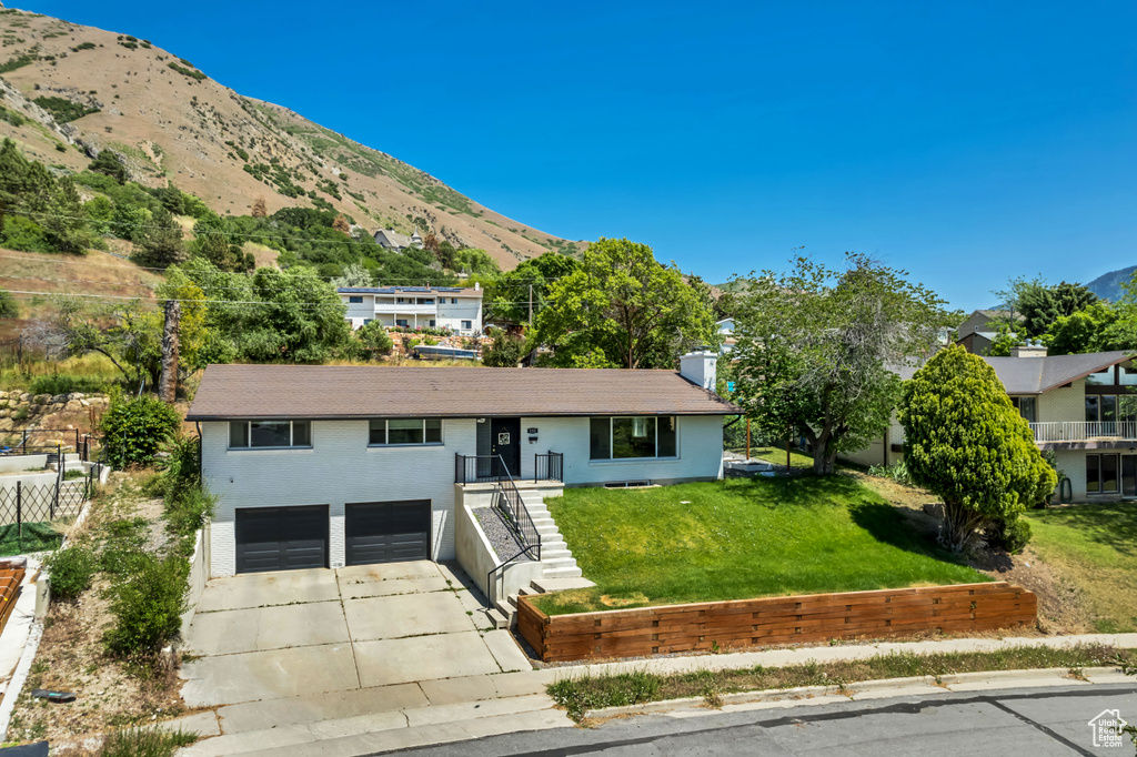 Single story home with concrete driveway, an attached garage, a mountain view, a front yard, and brick siding