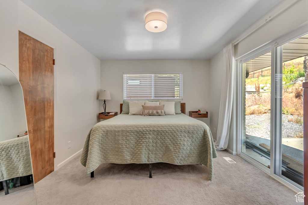 Bedroom with access to outside, multiple windows, and light colored carpet