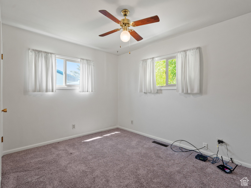 Carpeted spare room with healthy amount of natural light and a ceiling fan
