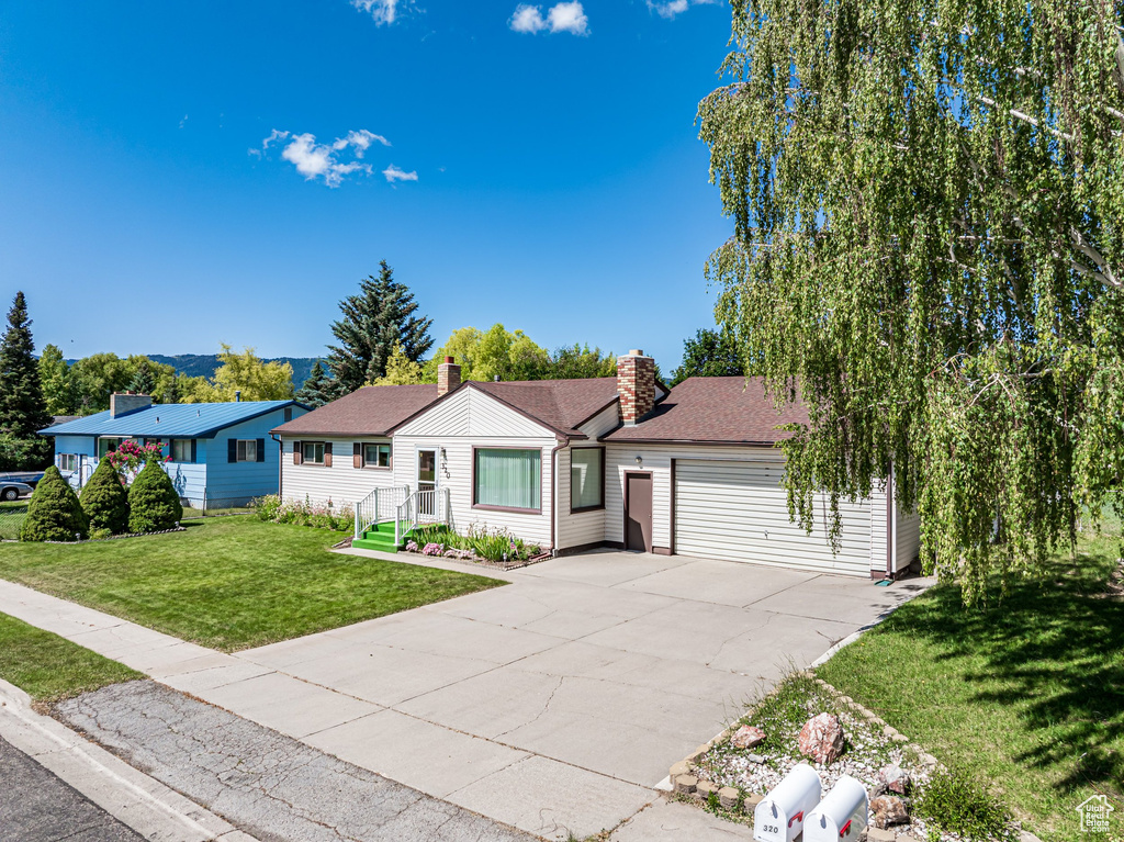 Ranch-style home with driveway, a front lawn, a chimney, and a garage
