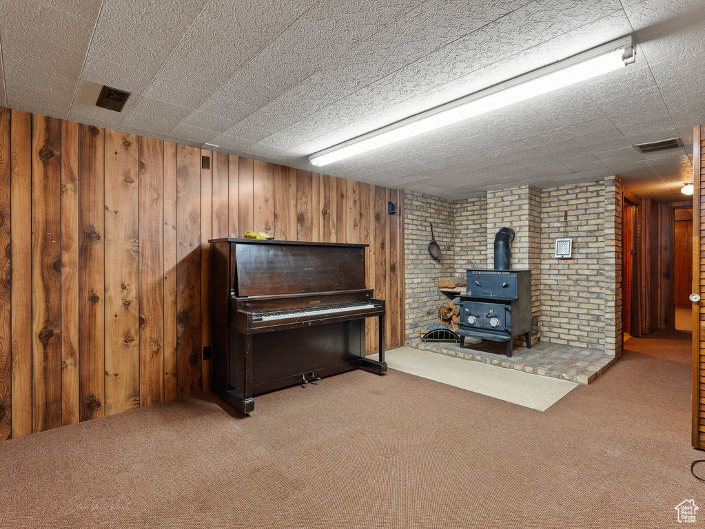 Sitting room with a wood stove, carpet, and wood walls