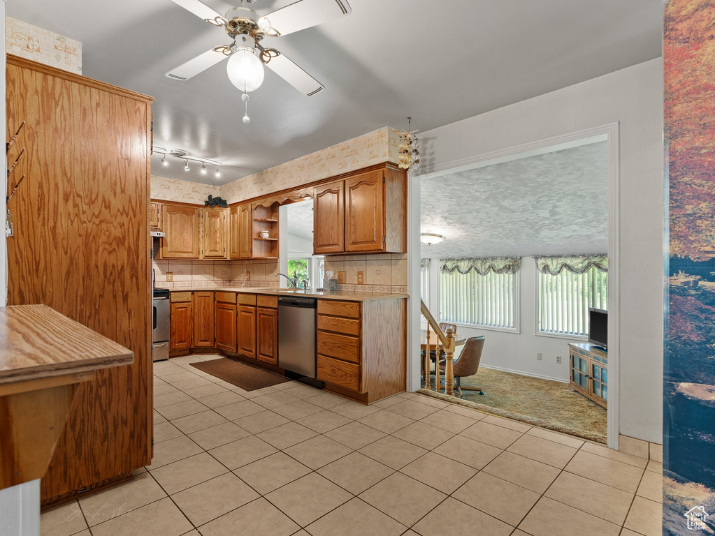 Kitchen featuring range, stainless steel dishwasher, open shelves, light countertops, and light tile patterned flooring