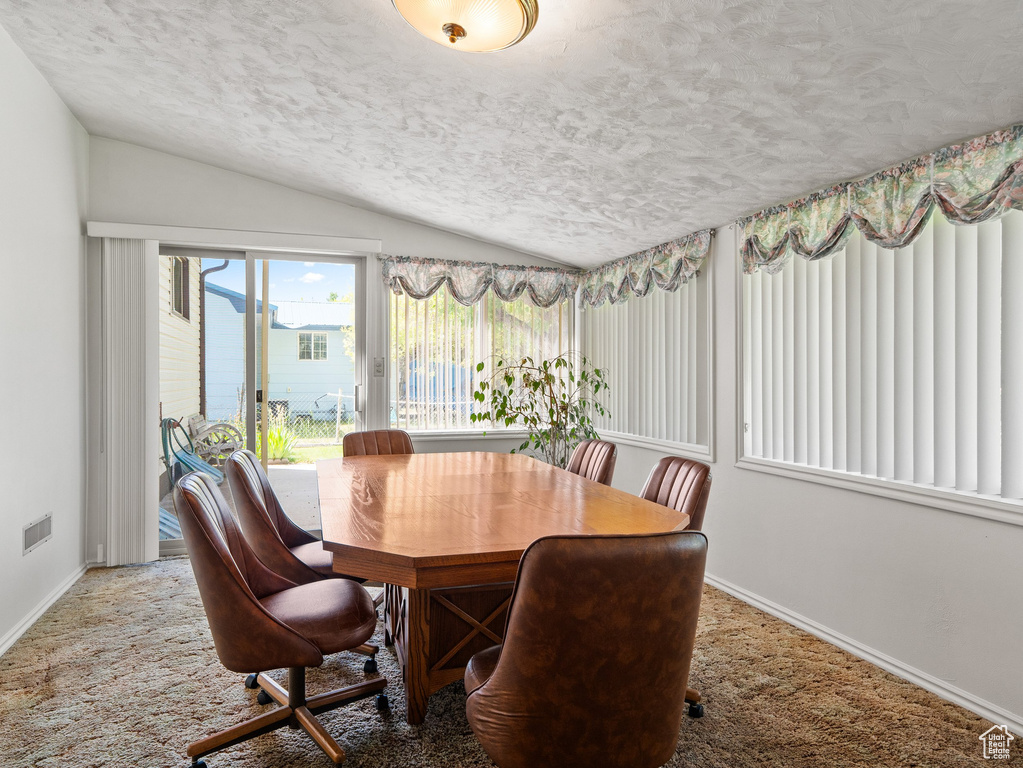 Dining area with vaulted ceiling, a textured ceiling, and carpet