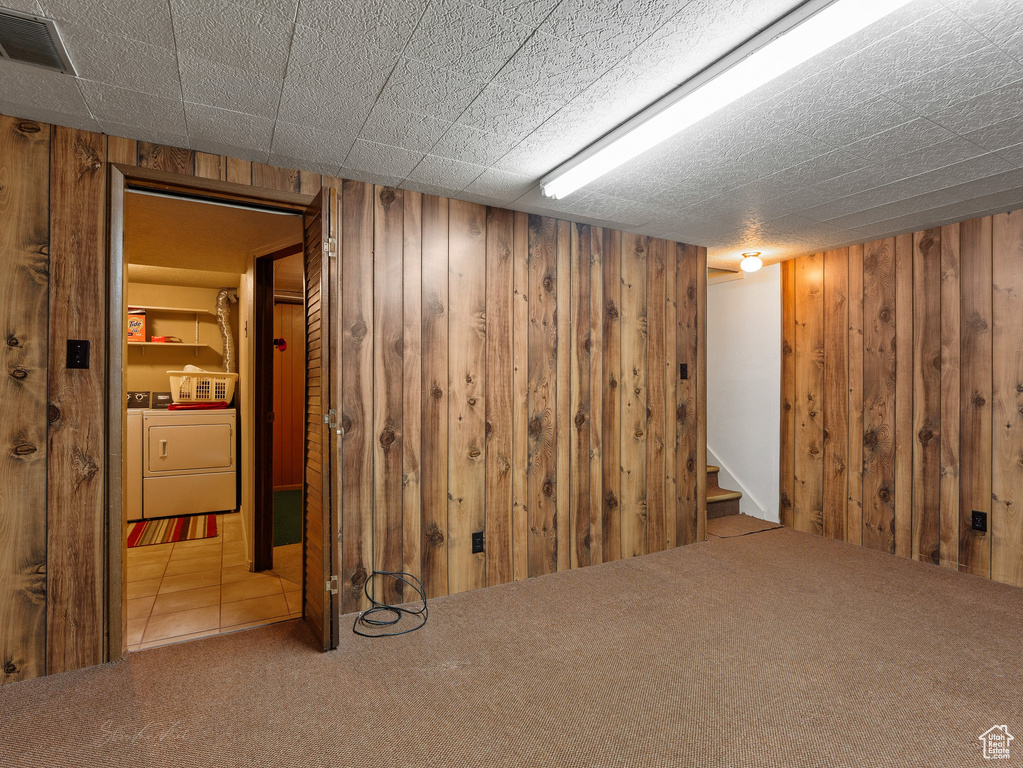 Finished below grade area with wood walls, washer and clothes dryer, carpet floors, and stairs
