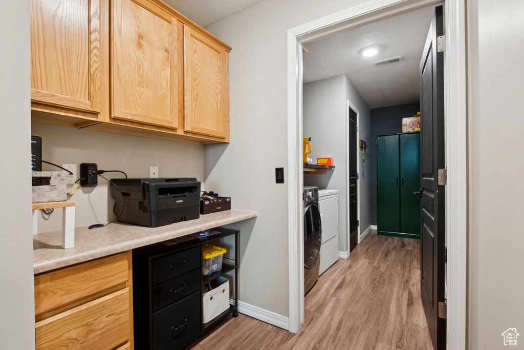 Laundry area with separate washer and dryer and light wood-type flooring