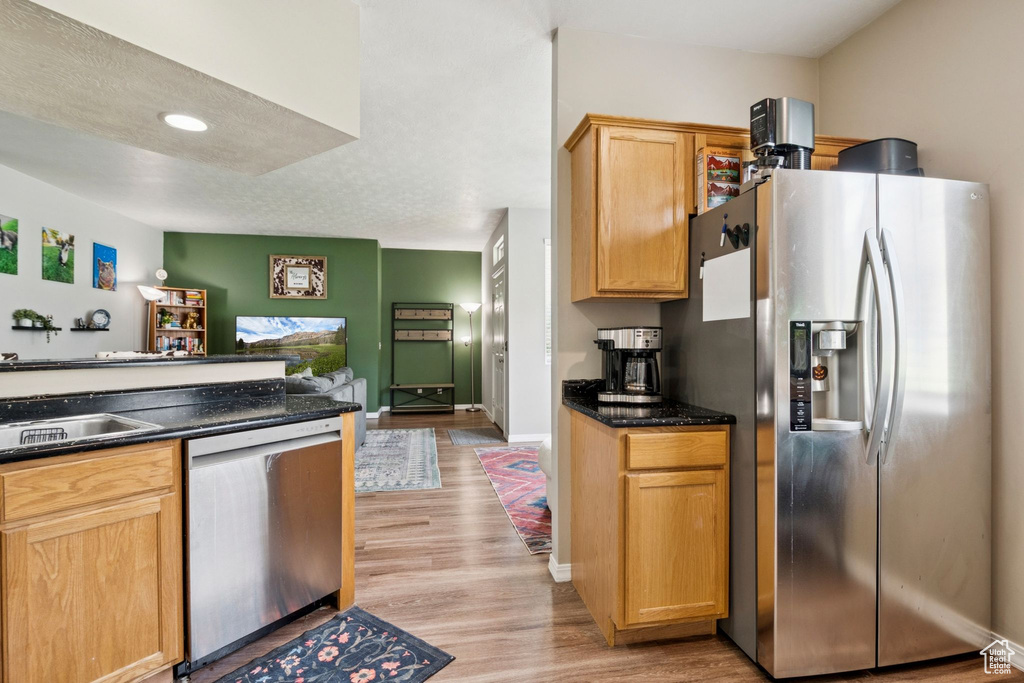 Kitchen featuring appliances with stainless steel finishes, light wood-type flooring, dark countertops, and light brown cabinets